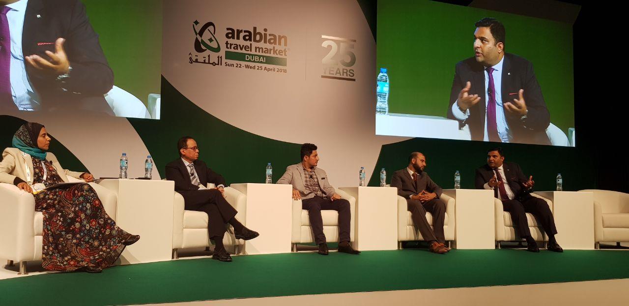 Mohsin Tutla speaking on a panel at the Arabian Travel Market in Dubai, shown on the stage screen