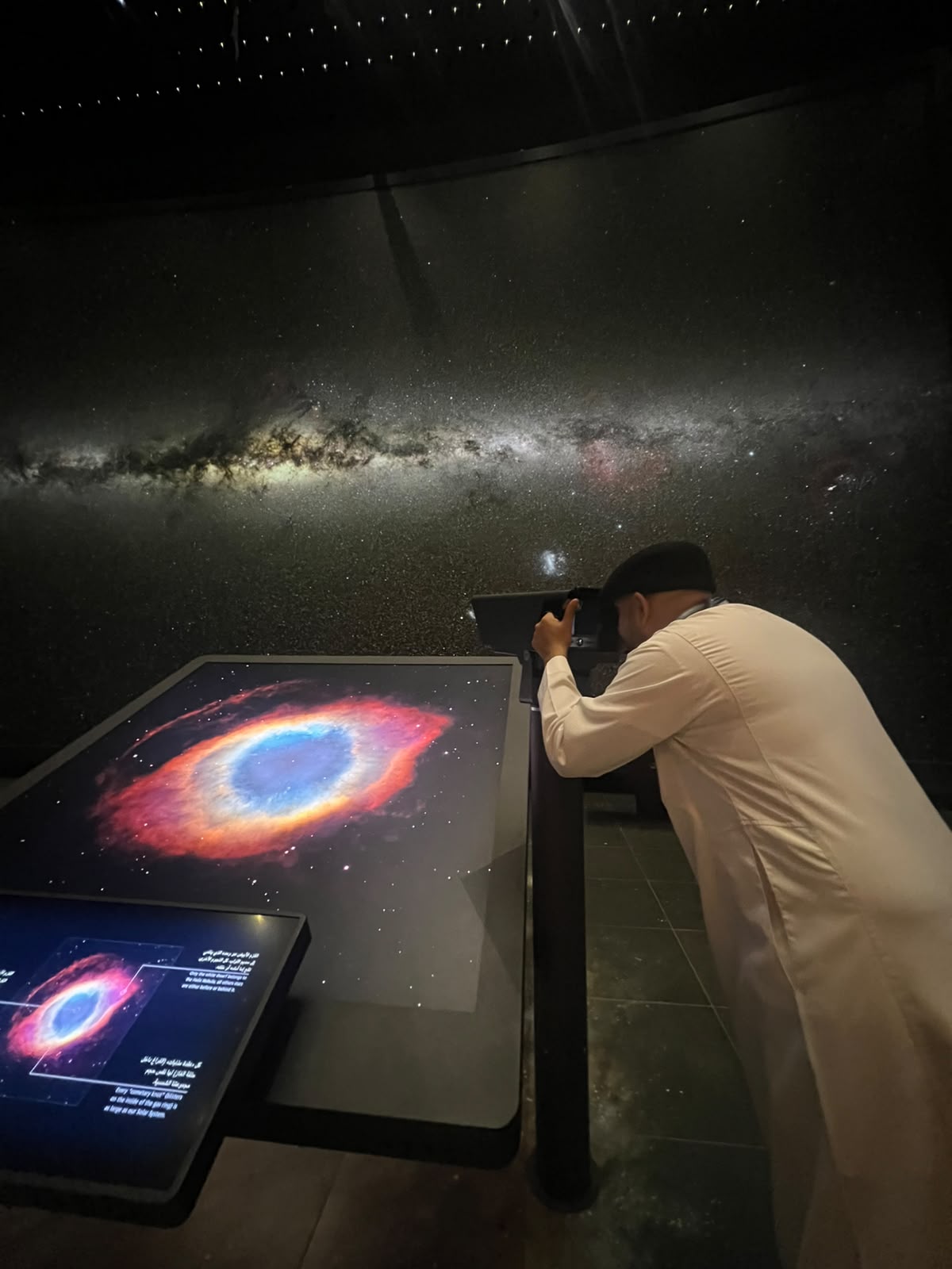 Mohsin Tutla looking through a telescope eyepiece at a museum exhibit
